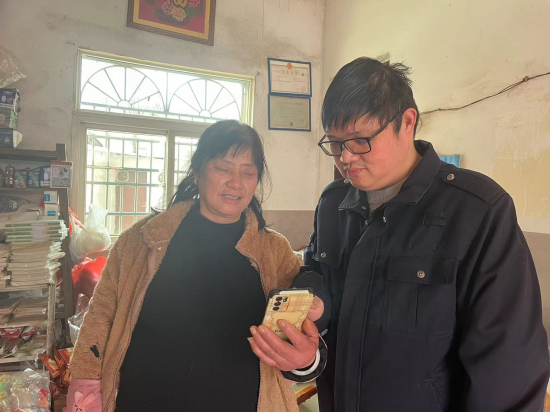 圖為東湖煙草志愿者(右)指導零售戶(左)查看卷煙防潮防霉知識