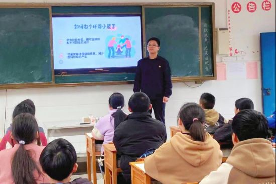 圖為志愿者在崇義縣城關(guān)小學(xué)上綠色環(huán)?？破照n