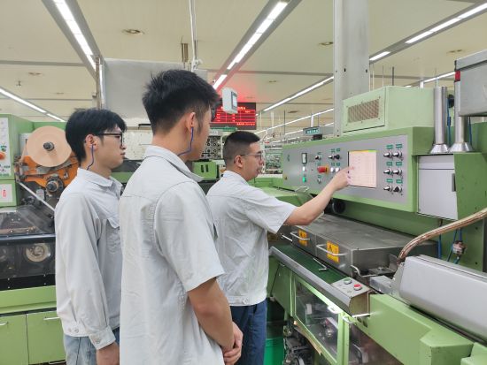 圖為該車間老師傅在機臺上對青年員工進行培訓(xùn)