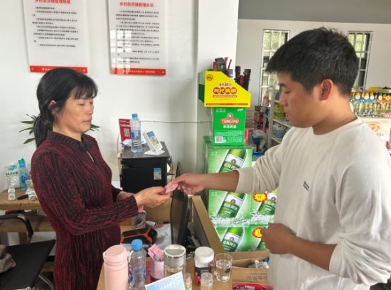 圖為村民在游長(zhǎng)蘭店內(nèi)用積分卡兌換物品