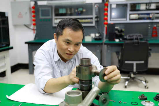 圖為倪風華勞模創(chuàng)新工作室成員在維修機器設備