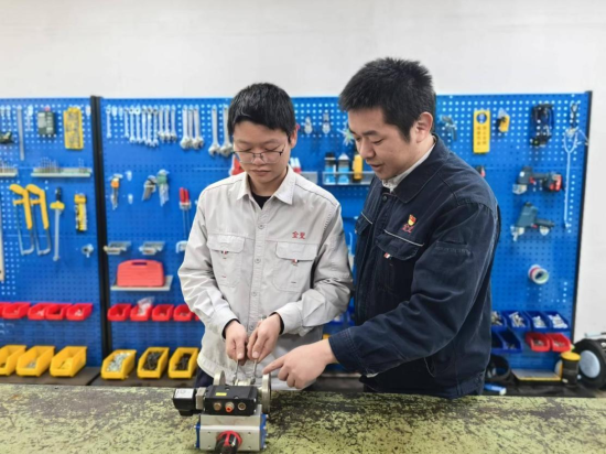 圖為青年機修工在師傅的指導下學習設備維修.png
