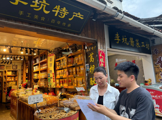 圖為專賣人員對景區(qū)商戶開展普法宣傳