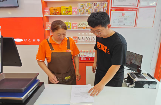 圖為工作人員向商戶發(fā)放宣傳手冊并講解違法后果.p