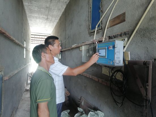 圖為煙技員唐傳東指導(dǎo)煙農(nóng)觸摸屏自控儀操作方法