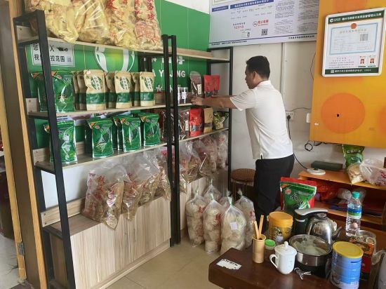 圖為客戶經(jīng)理吳至鴻正在整理零售戶店里的農(nóng)特產(chǎn)品.jpg
