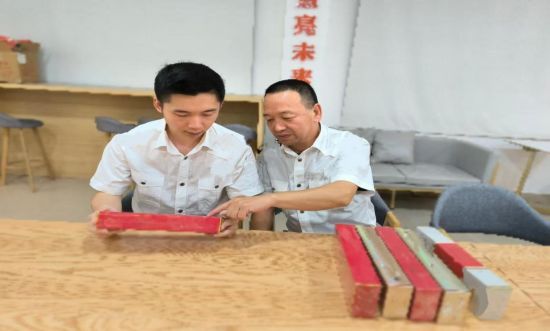 圖為青年員工向老隊員學習真假識別技巧