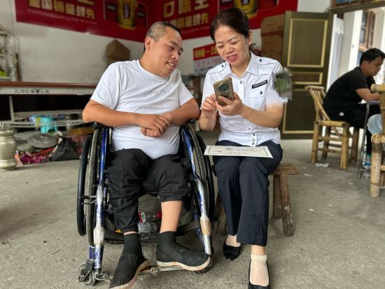 圖為江西德興煙草的工作人員指導(dǎo)殘疾客戶網(wǎng)上申請辦證