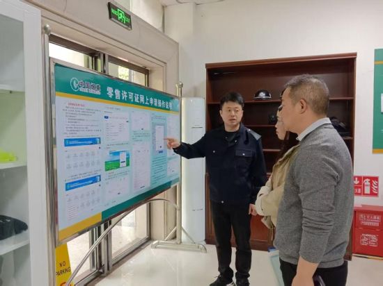 圖為市管員介紹零售許可證網(wǎng)上申請(qǐng)流程