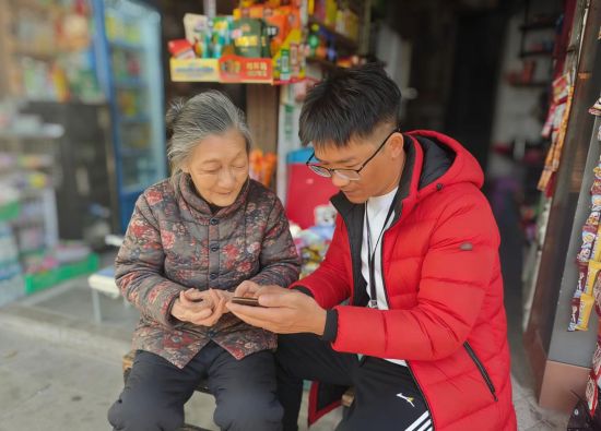 圖為客戶經(jīng)理指導(dǎo)客戶使用手機(jī)進(jìn)貨