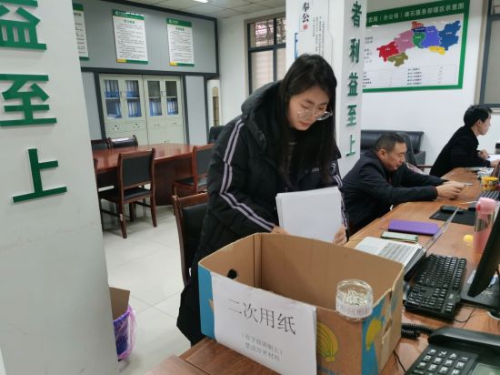 圖為員工將單面使用過的紙張整理放入專用回收箱