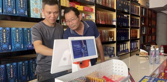 圖為客戶經(jīng)理指導(dǎo)零售戶使用終端系統(tǒng)