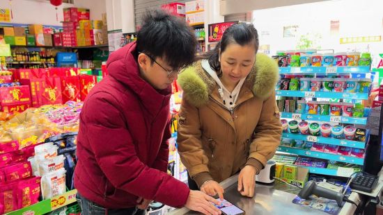 圖為尋烏縣煙草專賣局客戶經(jīng)理華洲教授零售戶申請許可證延續(xù)