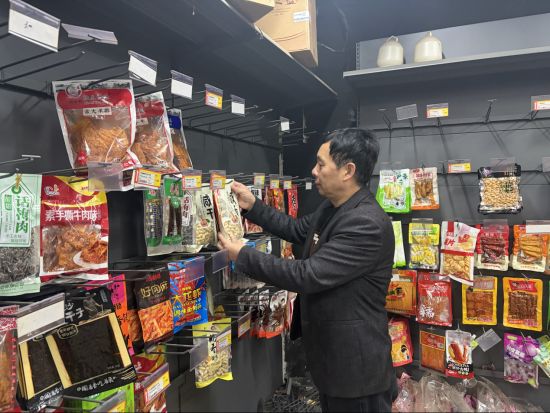 圖為余干煙草客戶經(jīng)理涂勇日常走訪幫助零售戶整理貨架