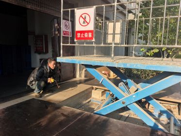 圖為維修技術(shù)人員正在對分揀升降平臺設(shè)備進行檢測維修