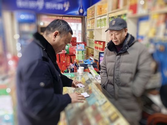 圖為萬(wàn)載煙草工作人員給高齡零售戶辦理許可業(yè)務(wù)