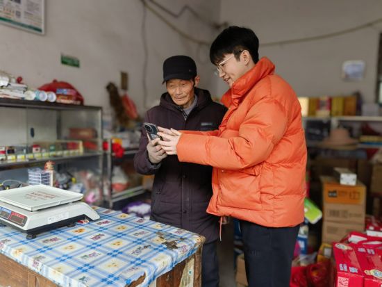 圖為江志良指導(dǎo)零售戶線上查詢相關(guān)法律法規(guī)