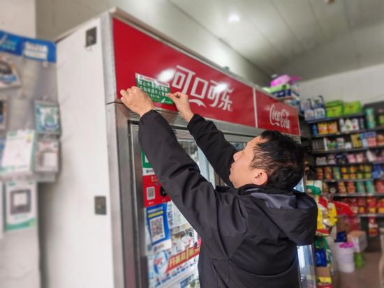 圖為稽查員幫助客戶粘貼警示標(biāo)語(yǔ)
