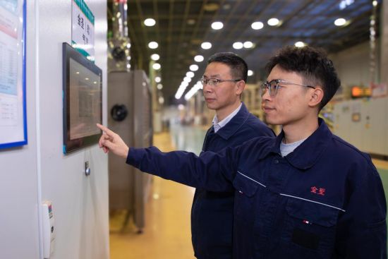 圖為車(chē)間工藝員正與操作工確認(rèn)松散回潮工序的流量參數(shù)