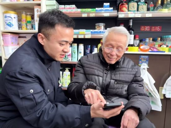 圖為弋陽煙草志愿者教老年零售戶在線上辦理延續(xù)